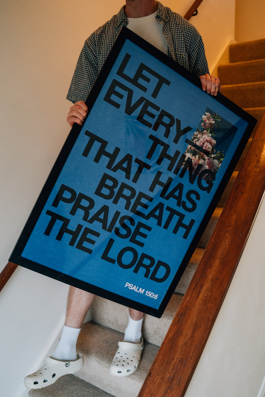 Person holding Let Everything That Has Breath art print, walking down stairs